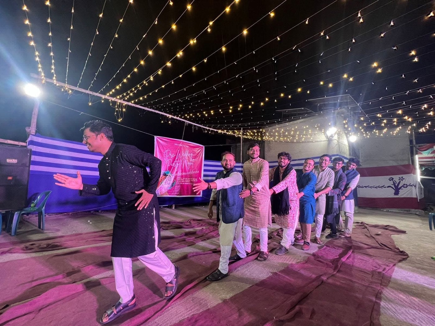 Friends dancing under string lights at a rooftop celebration