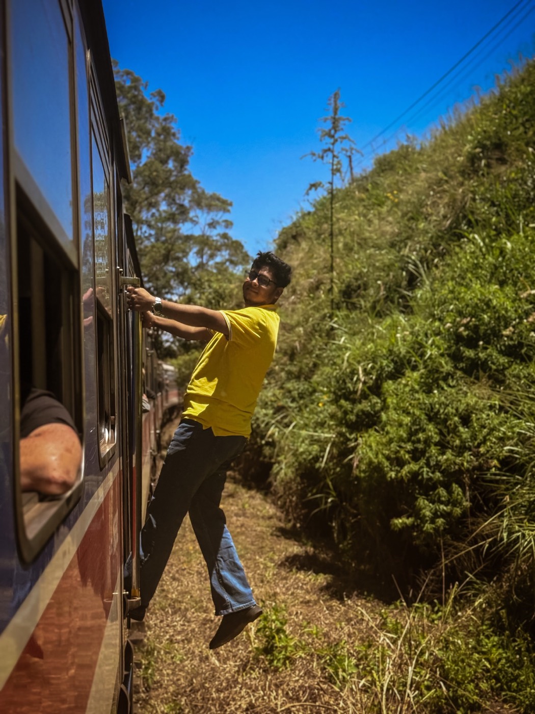 Leaning from a train on a sunny hillside route